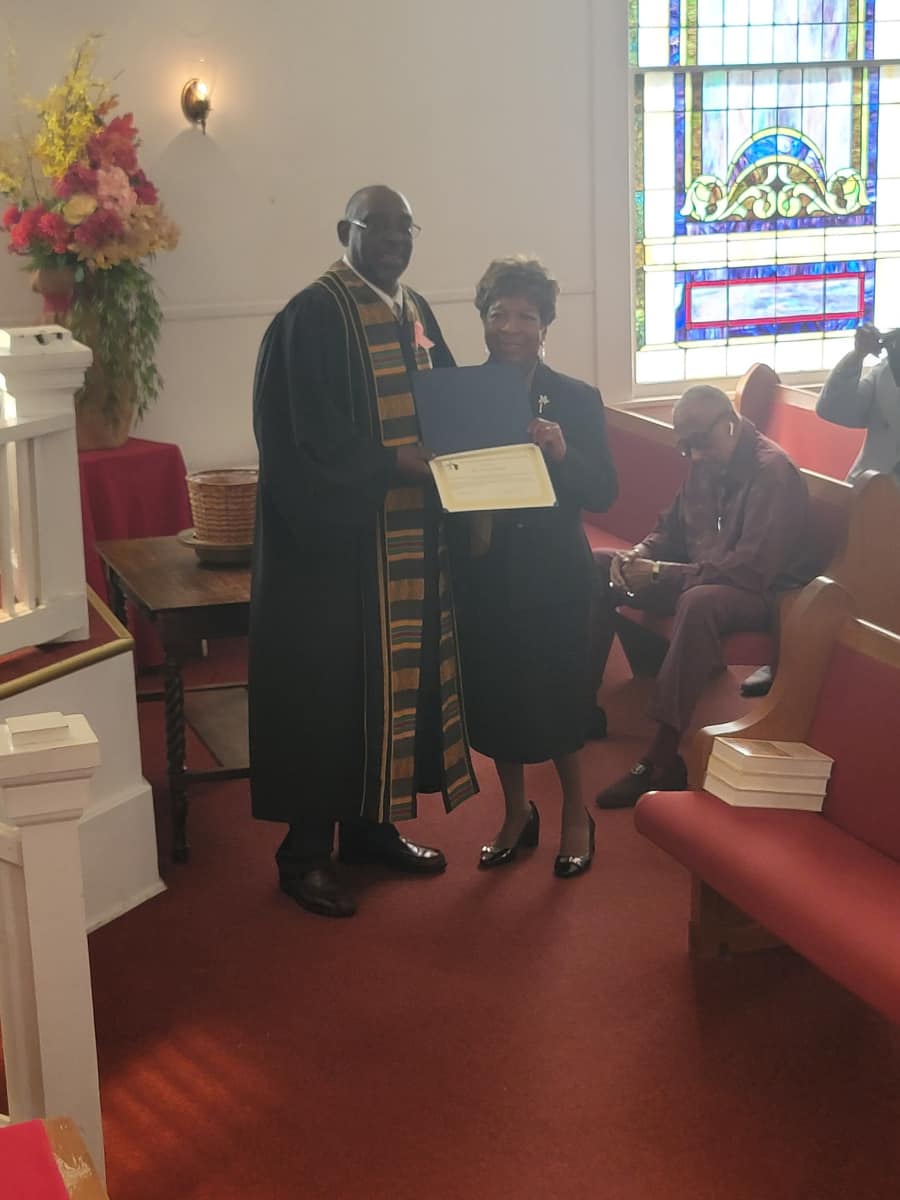 Pastor standing with a member holding a certificate